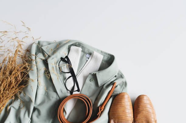 A light green jacket, white shirt, glasses, leather belt, and shoes arranged together, symbolizing political fashion.
